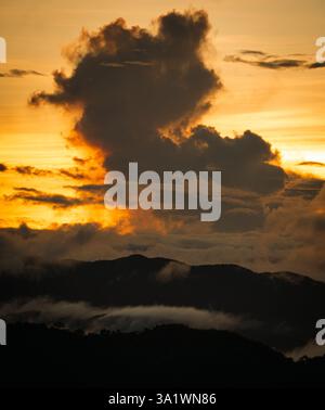 sagoma di una nuvola su una catena montuosa con un mare di nuvole al tramonto Foto Stock