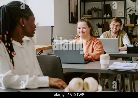 Ampia scelta di team birazziale di specialisti IT giovani e professionisti che chiacchierano tra loro durante la pausa pranzo Foto Stock