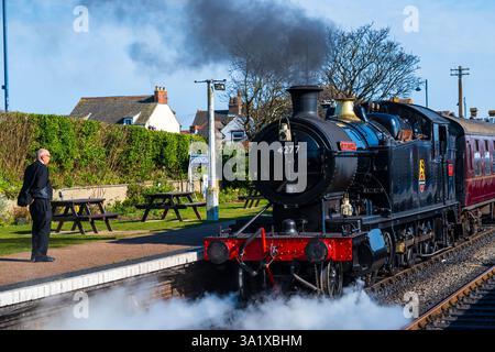 Sheringham, Norfolk, Regno Unito – 8 marzo 2025: Una guardia sbarca dal treno a vapore Hercules parte dalla stazione di Sheringham nel North Norfolk, Regno Unito Foto Stock