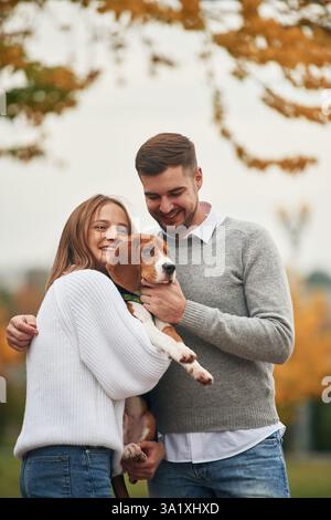 Sorridere, divertirsi. Una coppia adorabile è con il loro cane carino all'aperto. Foto Stock