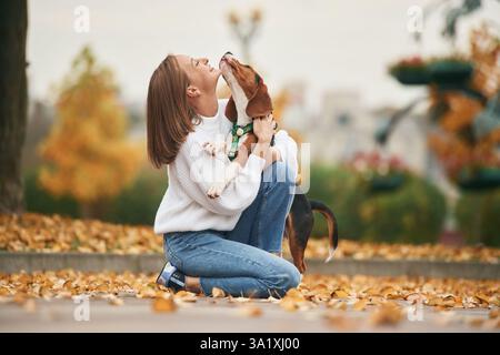 Vista laterale, gioco con animali domestici. La giovane donna è con il suo cane nel parco. Foto Stock