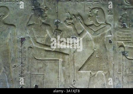 Il rilievo murale della Cappella di Iside nel Tempio Abido di Seti i mostra il re Seti che offre incenso alla dea Iside, seduta su un trono Foto Stock