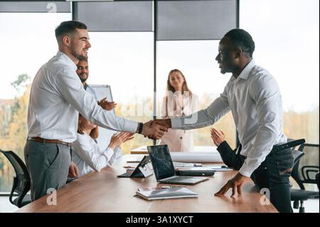 Stringere la mano. Un gruppo di impiegati lavora insieme in ambienti chiusi. Foto Stock