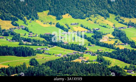Vista aerea panoramica della lussureggiante valle verde con case e colline boscose nel paesaggio estivo. Foto Stock