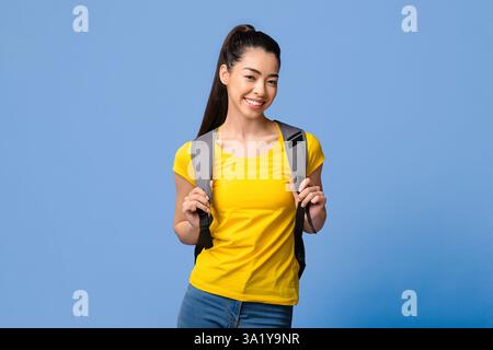 Giovane bella studentessa asiatica femminile con zaino in posa su viola Studio sfondo Foto Stock