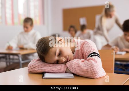 Ragazza della scuola che si trova e dorme alla scrivania Foto Stock