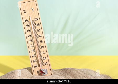 Termometro meteorologico in un mucchio di sabbia su sfondo colorato Foto Stock