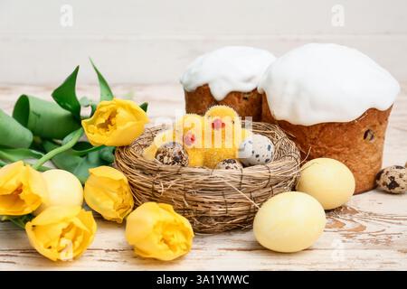 Dolci torte pasquali con uova, pulcini e splendidi fiori di tulipani su sfondo bianco in legno Foto Stock