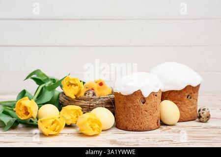 Dolci torte pasquali con uova, pulcini e splendidi fiori di tulipani su sfondo bianco in legno Foto Stock