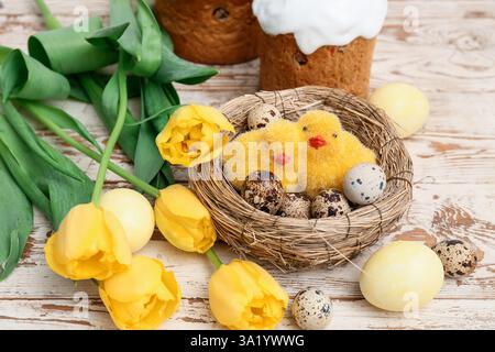 Dolci torte pasquali con uova, pulcini e splendidi fiori di tulipani su sfondo bianco in legno Foto Stock