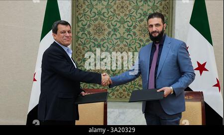 il presidente ad interim della Siria Ahmed al-Sharaa (R) stringendo la mano al comandante in capo delle forze democratiche siriane (SDF) Mazloum Abdi dopo la firma di un accordo, per integrare le istituzioni dell'amministrazione curda semi-autonoma nel nord-est nel governo nazionale, nella capitale siriana Damasco il 10 marzo 2025. Foto della Syrian Arab News Agency (sana)/UPI Credit: UPI/Alamy Live News Foto Stock