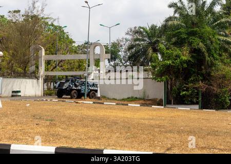 Un veicolo della polizia blindato parcheggiato vicino ad un ingresso recintato circondato dal verde a Enugu, Nigeria. Marzo 2025 Foto Stock