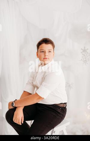 Ritratti in studio di un bambino di 11 anni, in ambiente natalizio, vestito elegante. Foto Stock