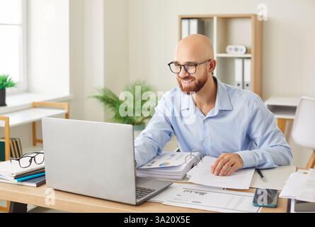 Addetto all'ufficio alla contabilità alla scrivania, alla ricerca di informazioni su Internet, al lavoro o allo studio, impegnato online Foto Stock