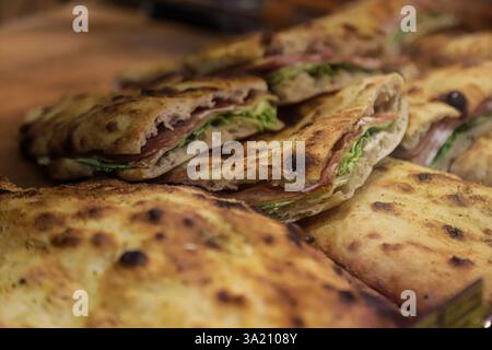 Focaccine appena fatte ripiene di carne e verdure sono servite su una superficie di legno in un vivace mercato di Bucarest, Romania, che mette in mostra Foto Stock