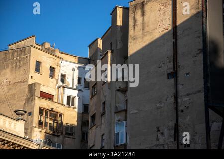 Il paesaggio urbano di Bucarest presenta edifici storici con diverse texture e finestre illuminate da un cielo blu luminoso, che enfatizza l'architettura Foto Stock