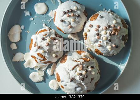 Muffin o cupcake ricoperti di glassa bianca e palline di cioccolato su un piatto azzurro su sfondo bianco. Vista dall'alto. Foto di alta qualità Foto Stock