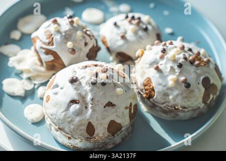 Muffin o cupcake ricoperti di glassa bianca e palline di cioccolato su un piatto azzurro su sfondo bianco. Vista dall'alto. Foto di alta qualità Foto Stock