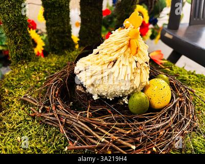 Statua di gallina realizzata a mano con dettagli vivaci che poggiano sulle uova in un nido rustico Foto Stock