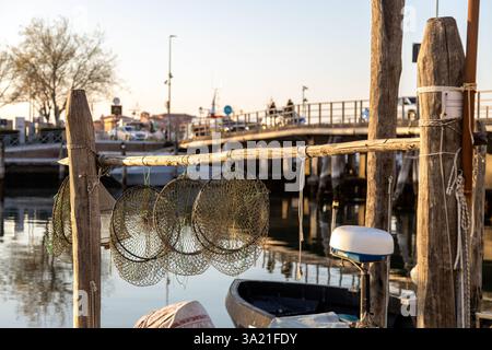 Reti da pesca tradizionali in riva all'acqua al tramonto, che catturano il patrimonio ittico veneziano a Sottomarina, Chioggia, Italia Foto Stock