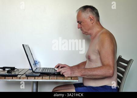 Uomo d'affari, libero professionista, più di 60 anni in vacanza lavorando con computer portatile e telefono cellulare, Pattaya, Chonburi, Thailandia, Asia Foto Stock