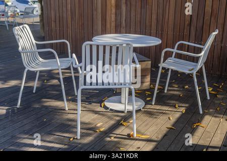 Mobili da esterno bianchi che gettano ombre su un ponte di legno illuminato dal sole, presi a Wando, Corea del Sud, Asia Foto Stock