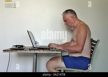 Uomo d'affari, libero professionista, più di 60 anni in vacanza lavorando con computer portatile e telefono cellulare, Pattaya, Chonburi, Thailandia, Asia Foto Stock