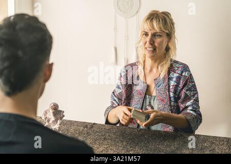 Lettore di tarocchi che mescola il mazzo di tarocchi davanti al suo cliente maschio Foto Stock
