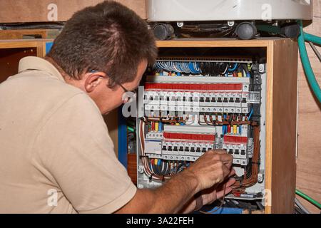Tecnico che lavora all'interno di un pannello di controllo elettrico per la manutenzione Foto Stock