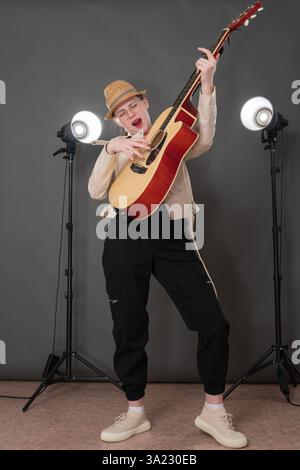Chitarrista e cantautrice femminile espressiva che suona la chitarra classica e canta la canzone con gli occhi chiusi, in piedi per tutta la lunghezza sul palco. Mus giocoso Foto Stock