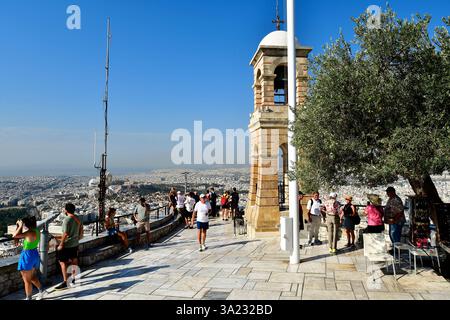 Atene, Grecia - 23 settembre 2024: Turisti non identificati e campanile sulla terrazza panoramica dal colle di Licabetto con panorama sul mare di ​​house Foto Stock
