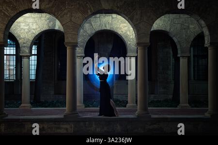 Silhouette di donna contro la luce blu negli archi di notte Foto Stock