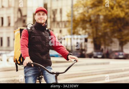Corriere in bicicletta in piedi con borsa che consegna cibo in città Foto Stock