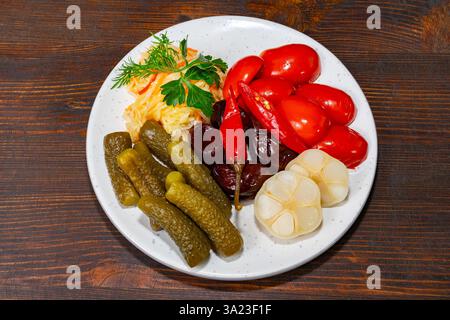 Una varietà di verdure sott'aceto è esposta su un piatto bianco, con peperoni rossi, sottaceti, barbabietole, aglio, e cavolo. Questa vivace collezione è Foto Stock