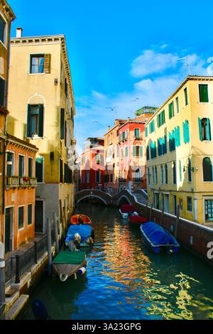 Un canale panoramico a Venezia, in Italia, con colorati edifici storici e barche ormeggiate lungo l'acqua. Le riflessioni sul canale contribuiscono al fascino della città. Foto Stock
