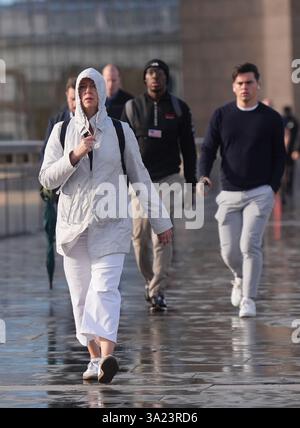 Persone che camminano in condizioni di vento sul London Bridge mentre la tempesta Lilian colpisce il Regno Unito. Data foto: Venerdì 23 agosto 2024. Foto Stock