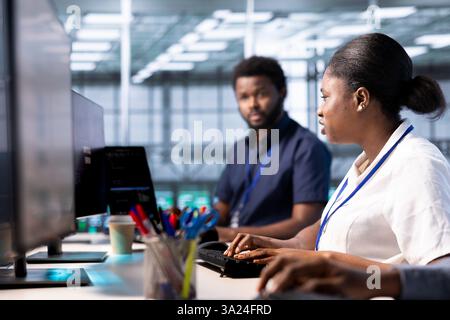 Amministratore afroamericano nello spazio di lavoro del data center che esegue test diagnostici di sistema e utilità di controllo degli errori per risolvere i problemi. Donna in un server hub alla ricerca di problemi di rete che influiscono sulle prestazioni dei sistemi di perforazione Foto Stock