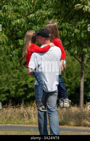 padre che porta due figli Foto Stock