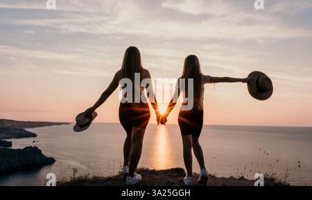 Silhouette di due donne che si tengono per mano al tramonto Foto Stock