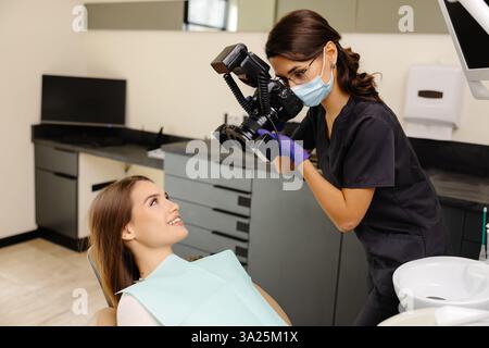 Dentista che fotografa con una fotocamera professionale il risultato del suo lavoro in clinica. Foto Stock