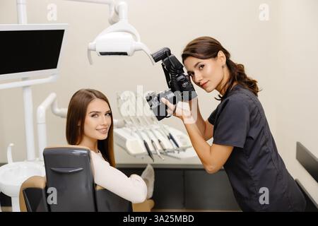 Dentista che fotografa con una fotocamera professionale il risultato del suo lavoro in clinica. Foto Stock