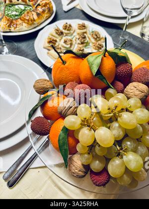 Vari tipi di frutta (uva, mele, noci, litchi, arance) su una tavola di Natale. Festività e Natale. Direttamente sopra. Foto Stock