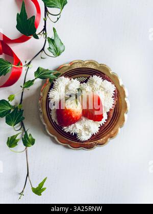 Torta a forma di cuore di San Valentino con panna e fragole. Direttamente sopra. Foto Stock