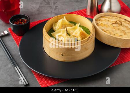 Gnocchi di gamberi al vapore in una vaporiera di bambù con foglia di banana, serviti con salsa di soia al peperoncino Foto Stock