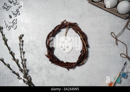 corona pasquale di rami di viti con filetto su sfondo grigio con copyspace. decorazione con uova Foto Stock