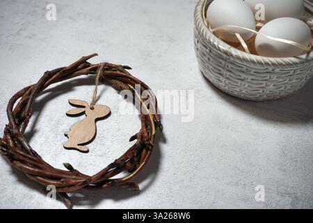 corona pasquale di rami di viti con filetto su sfondo grigio con copyspace. decorazione con uova Foto Stock