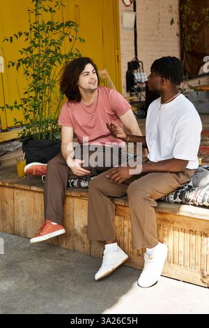 Una felice coppia gay condivide sorrisi e storie con un drink in un vivace caffè. Foto Stock