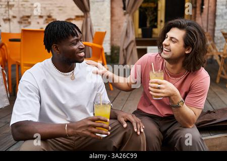 Una bella coppia condivide un momento di gioia con un drink in mano, seduto da vicino in un vivace caffè. Foto Stock