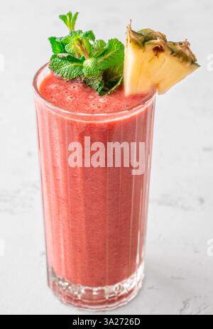 Frullato tropicale cremoso con ciliegia, banana e ananas, guarnito con menta e ananas Foto Stock