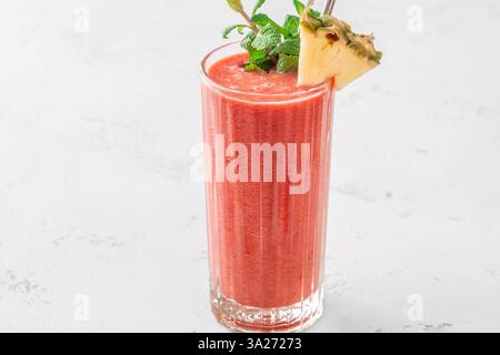 Frullato tropicale cremoso con ciliegia, banana e ananas, guarnito con menta e ananas Foto Stock